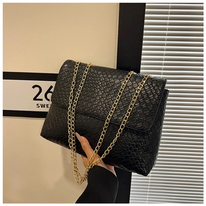 Detailed view of black woven leather texture and gold metal chain strap on handbag