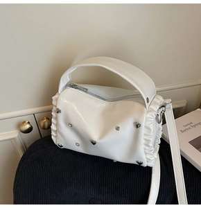 Detail of white glossy shoulder bag featuring silver heart buckle and pleated sides