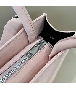 Detail of silver metal zipper and smooth stitching on the light pink crossbody bag