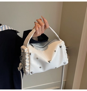 Close-up of white ruffle shoulder bag with heart rivets and silver metal details