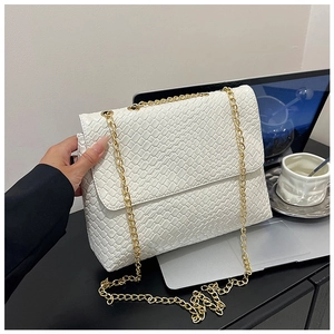 Close-up of white woven shoulder bag with gold chain strap on an office desk