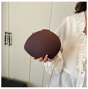 Dark wine red oval acrylic shell evening clutch with gold chain strap held by model