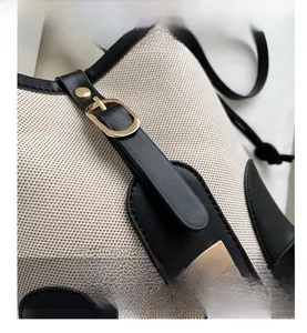 Detail view of cream canvas and black leather contrast stitching with gold buckle