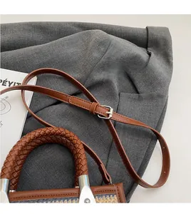 Detail of adjustable leather shoulder strap and woven handle on contrast color bag