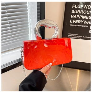Détail d'une pochette en acrylique marbré orange avec poignée en métal argenté et chaîne