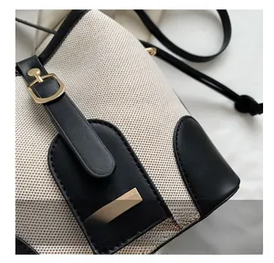 Detailed close-up of neat stitching on canvas and black leather bucket bag contrast