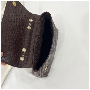 Detailed macro view of dark brown woven texture flap bag with gold chain hardware