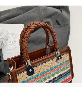 Detail of colorful striped woven tote bag with brown braided handles and silver hardware