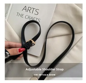 Adjustable black faux leather strap with gold buckle detail on a canvas shoulder bag