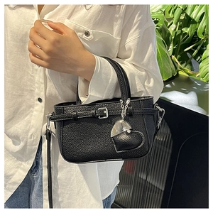 Detail of black litchi grain leather bag featuring heart charm and silver hardware