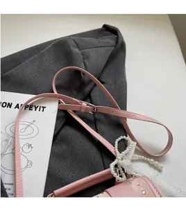 Pink leather shoulder bag detail with pearl bow, lace trim and adjustable strap