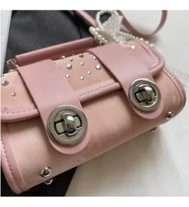 Detail of light pink cylindrical bag with silver studs and circular metal clasp closure