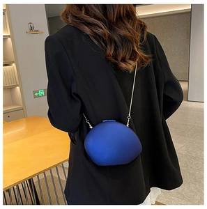 Detail of bright blue pebble-shaped acrylic clutch with gold chain strap on black suit