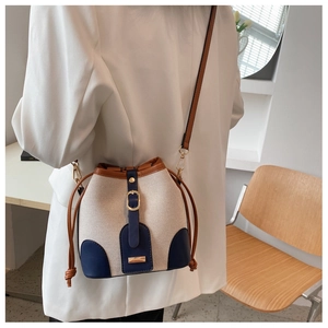 Detail of canvas bucket bag with leather contrast and gold hardware on model