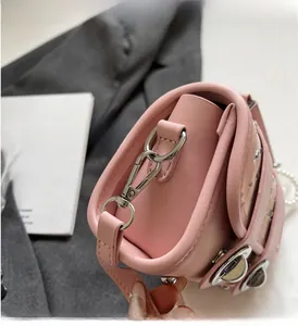 Close-up of pink woven bag showing silver metal hooks, pearl strap, and fine stitching