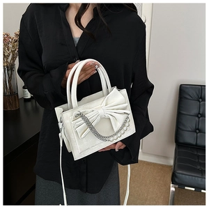 Detail of white bow handbag with pearl chain and elegant metallic charms decoration
