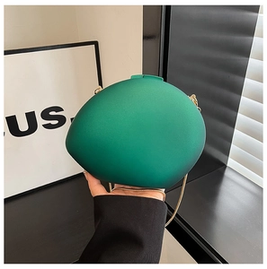 Macro shot of green oval acrylic evening bag with matte finish and gold chain strap