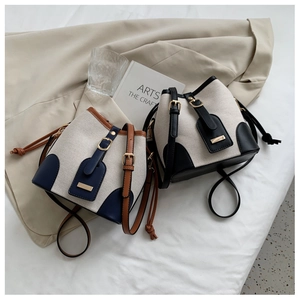 Detail of canvas bucket bags with contrast leather trim and adjustable shoulder straps