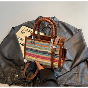 Detailed view of woven striped tote bag with leather handles and silver hardware