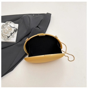 Detail view of yellow oval evening clutch bag with golden chain and black lining