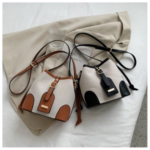 Detail of canvas bucket bags in brown and black leather trim with metal buckles