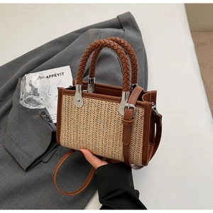 Detailed view of woven straw bag texture with brown leather handle and silver hardware