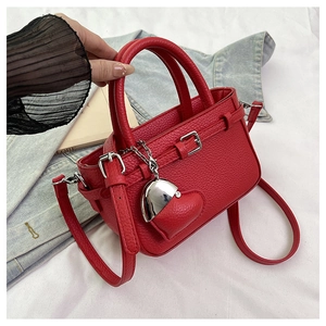 Close-up of red lychee textured handbag with silver buckle and heart pendant