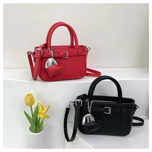Close-up of pebble leather handbags in black and red with heart pendants on a white pedestal