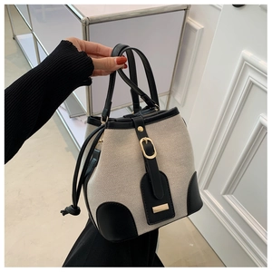 Detail of color-block canvas bucket bag featuring black leather trim and golden buckle
