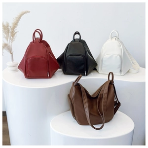 Modern geometric multi-way leather bags in red, black, white, and brown on display
