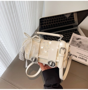 Detail view of cream handbag with pearl bow, lace ribbon, and crystal accents