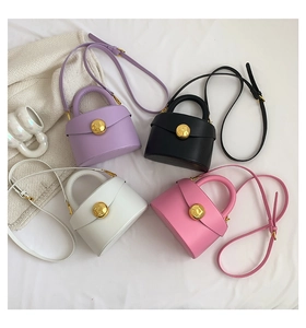 Four mini crossbody bags in diverse colors with gold ball clasp on textured white fabric