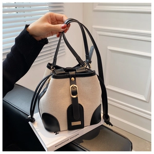 Detail of canvas bucket bag with contrast leather trim and golden metal hardware