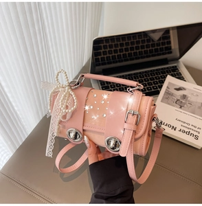 Detail of pink leather handbag featuring pearl bow decoration and crystal accents