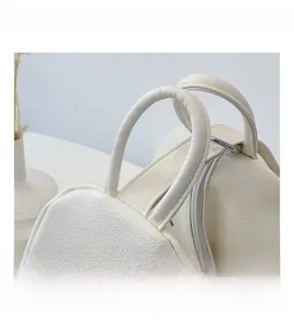 Detail of white pebbled leather bag with curved handles and zipper closure