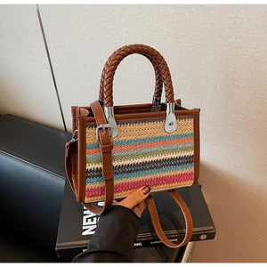 Detail of colorful woven handbag with brown leather trim and round braided handles