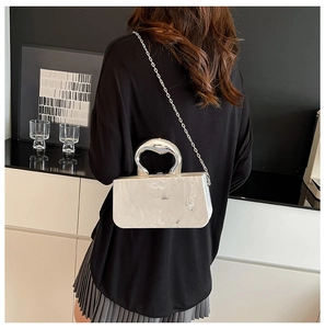Détail du sac à main en acrylique marbré blanc avec poignée cœur et bandoulière argent