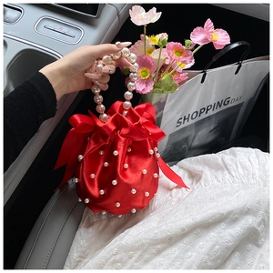 Detail of red satin handbag with white faux pearl embellishments and large side bows