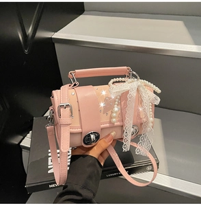 Detail of pink cylinder bag with rhinestones, lace bow, and pearl decorative charms