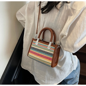 Macro view of multi-color woven pattern with brown leather handle and silver metal hardware