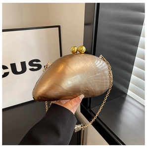 Detail of a gold acrylic clutch bag with spherical metal clasp and chain strap for evening