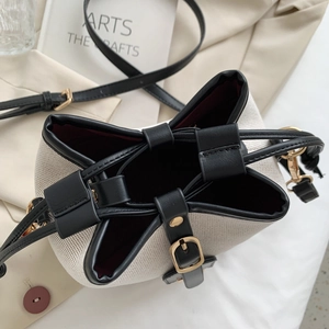 Close-up of canvas bucket bag with black leather trim and gold drawstring hardware