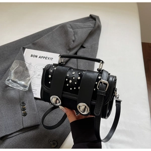 Detail of black leather punk shoulder bag with silver rivets and metallic buckle knobs
