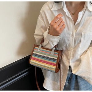 Detail of colorful woven shoulder bag with brown leather trim and metallic silver hardware