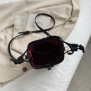 Internal view of black canvas bucket bag featuring burgundy lining and a zipper pocket