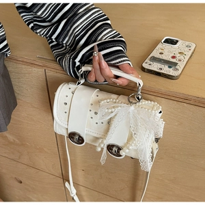Detailed shot of white shoulder bag featuring lace bow, pearl chain and silver hardware