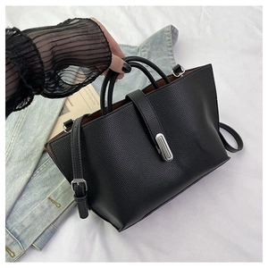 Detail of black lychee grain leather tote bag with silver metal lock and adjustable strap