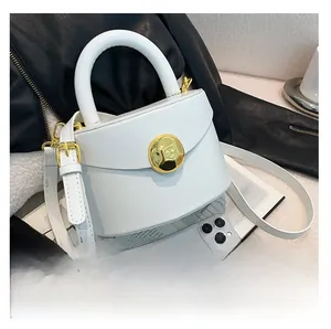 Macro view of white bucket bag with gold circular metal buckle and textured leather finish