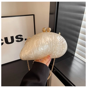 Detail view of pearl white acrylic evening clutch with marble texture and gold kiss-lock