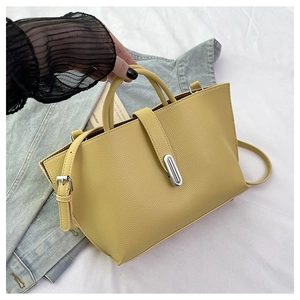 Detail of yellow pebbled leather tote bag with silver metal clasp on casual background
